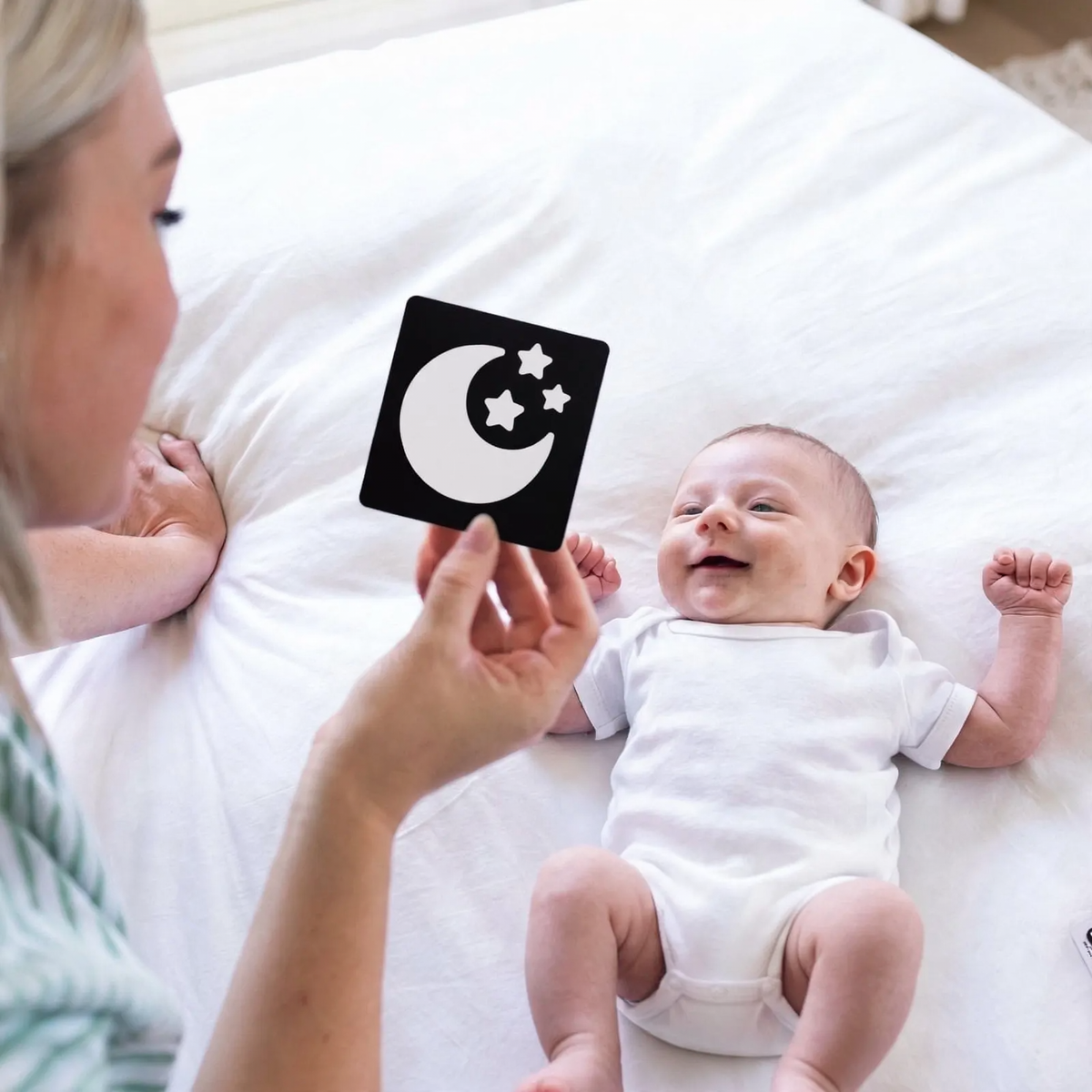Baby looking at a black and white visual card held by a parent