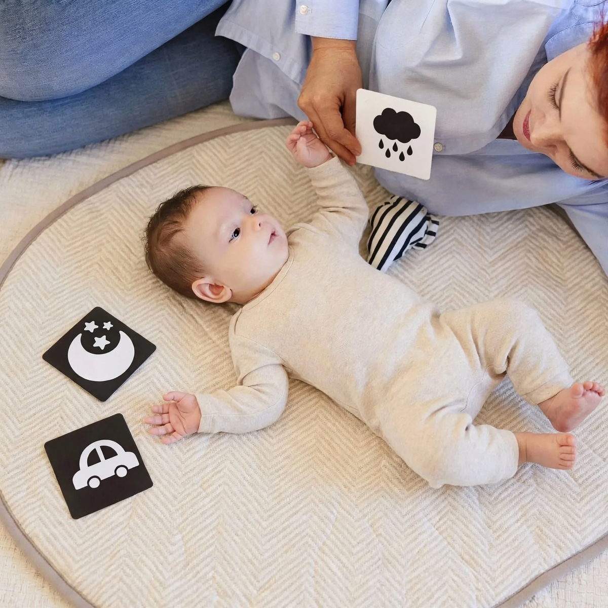 Baby looking at different black and white visual cards held by a parent